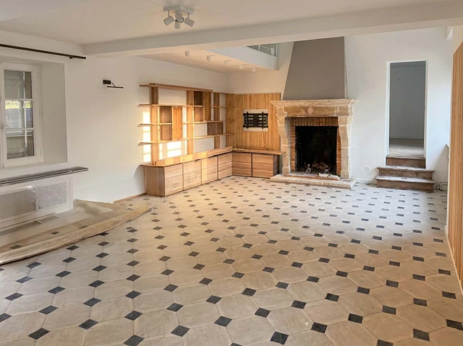 Pièce vide en cours de rénovation, salon avec cheminée ancienne en pierre calcaire, hotte métallique moderne