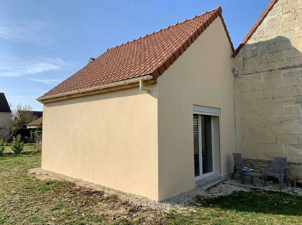 Chantier de construction résidentielle avec fondations en béton coulé et maison à ossature bois en cours d'édification