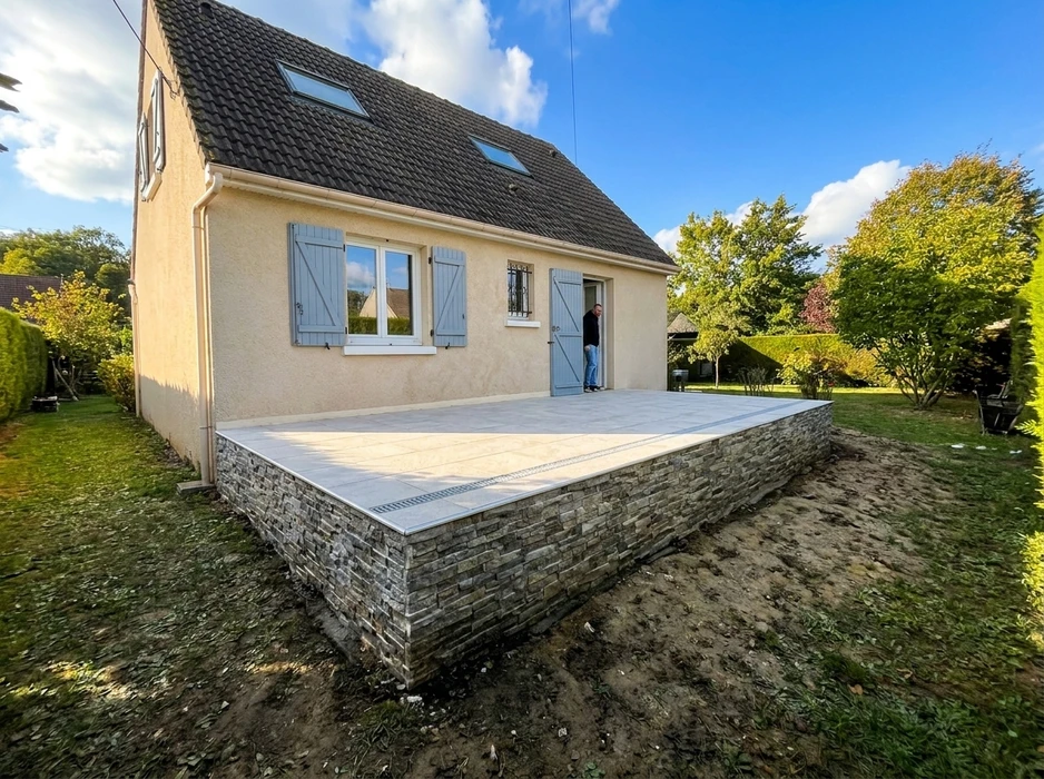 Chantier ext&eacute;rieur avec ouvrier en salopette bleue lissant une dalle de b&eacute;ton fra&icirc;chement coul&eacute;e &agrave; l'aide d'une taloche