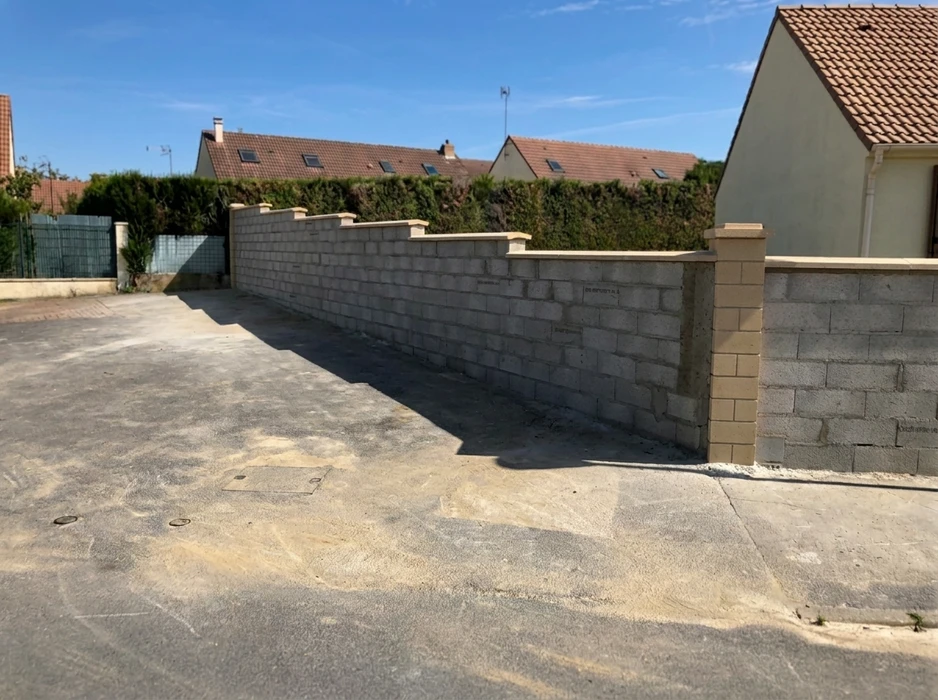 Chantier de construction neuf en extérieur, un ouvrier positionne un profilé au sol sur une dalle béton