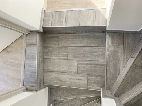 Homme en t-shirt blanc installant du parquet en bois dans une pi&egrave;ce lumineuse avec murs blancs et fen&ecirc;tre
