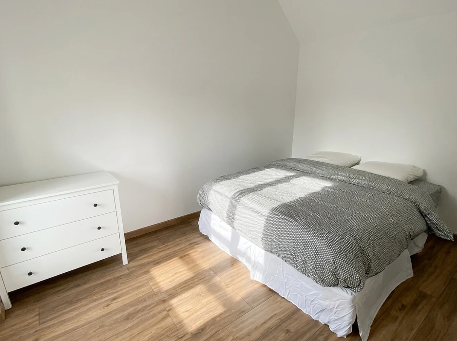 Pièce vide rénovée, sol en parquet stratifié chêne clair, murs blancs, fenêtre PVC double vitrage avec vue sur bâtiment extérieur